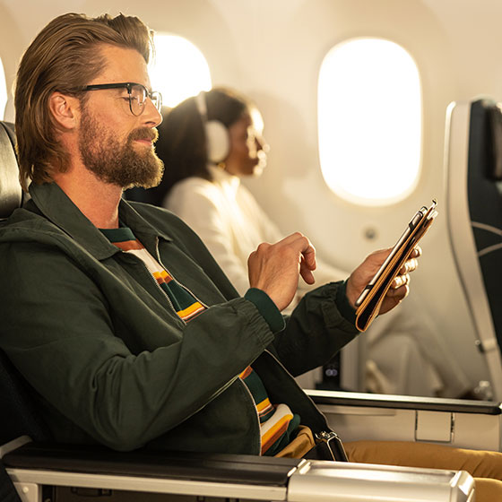 Man on a tablet device sitting on an airplane
