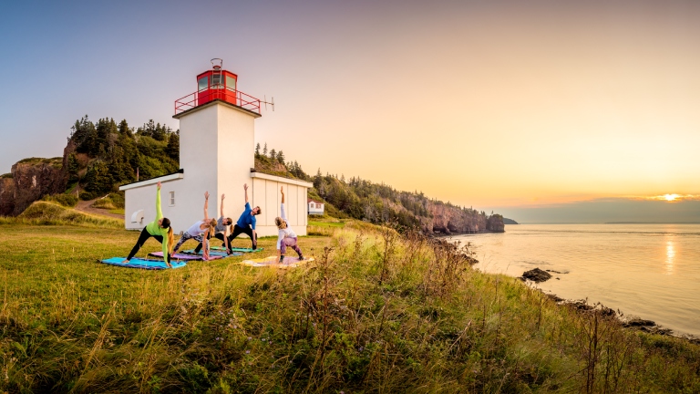 Group doing yoga in front of lighthouse